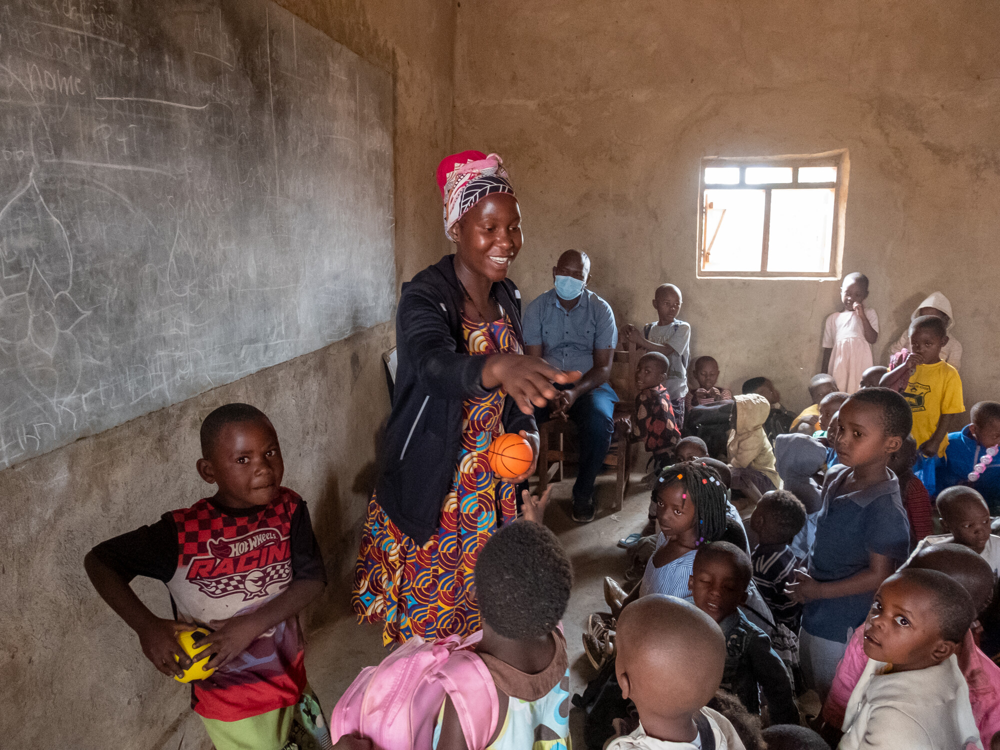 A Ugandan teacher stands in front of a group of young students