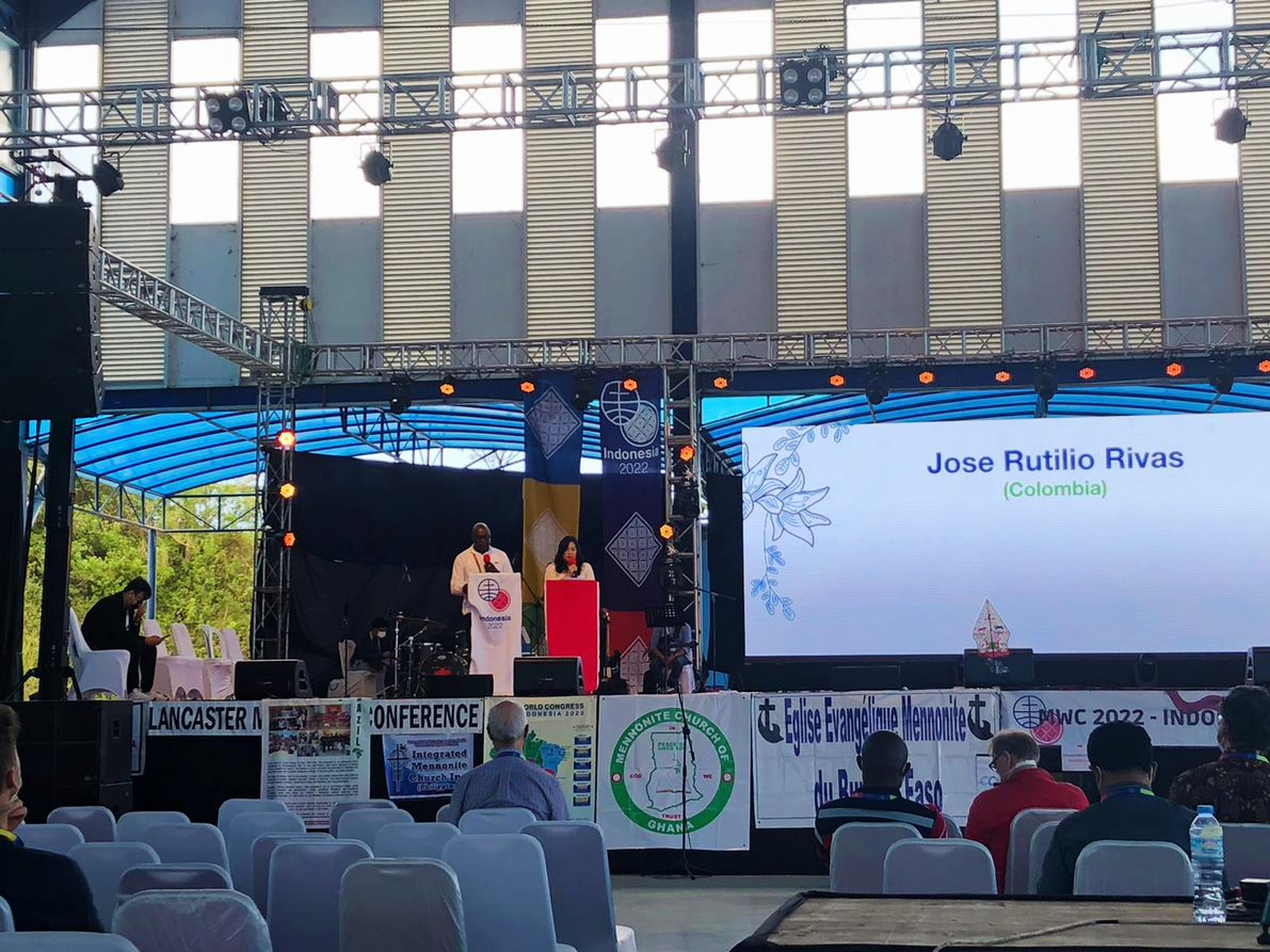 Two people stand at podiums on stage 