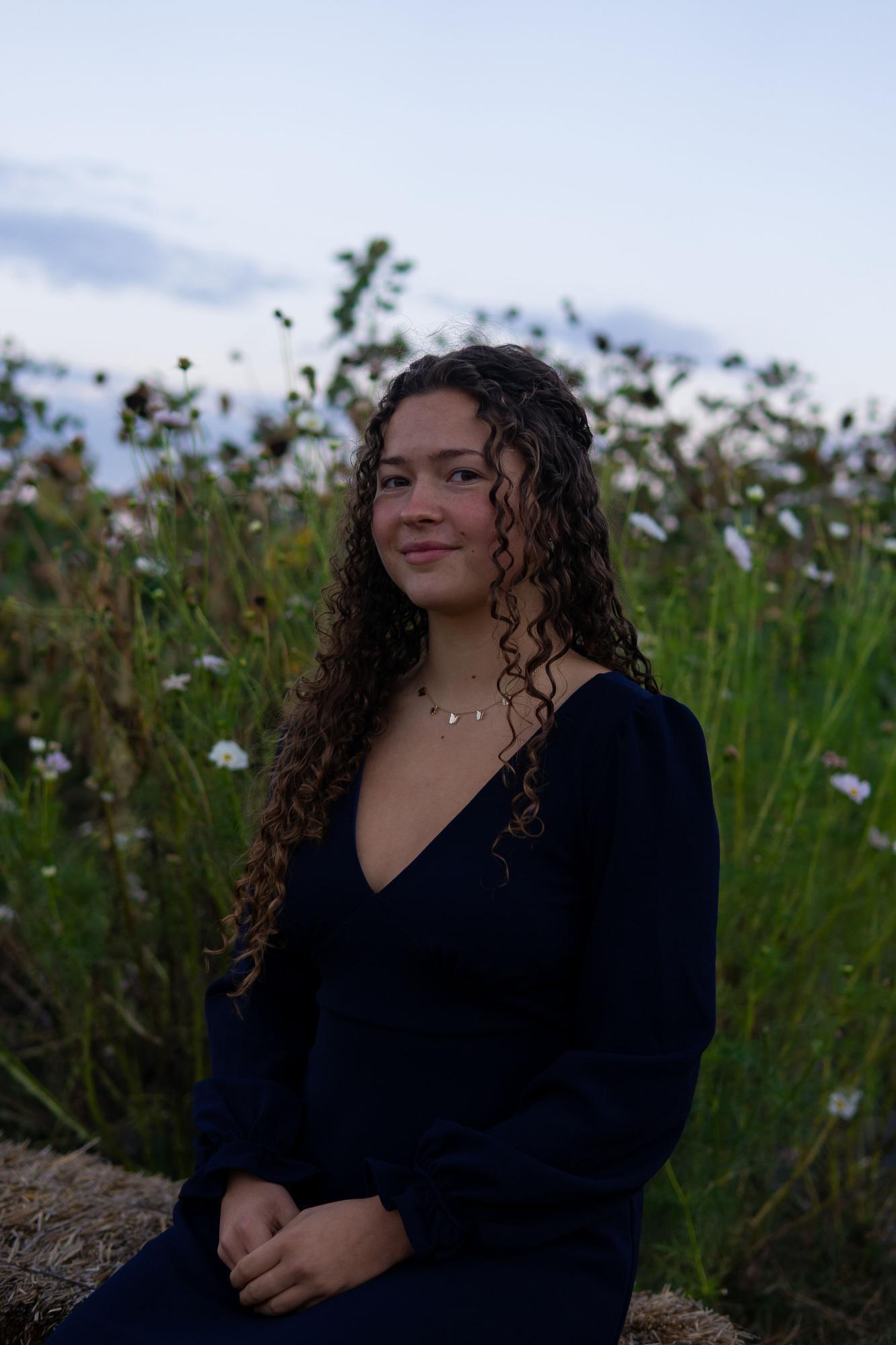 Allison sitting for a photo in front of a field