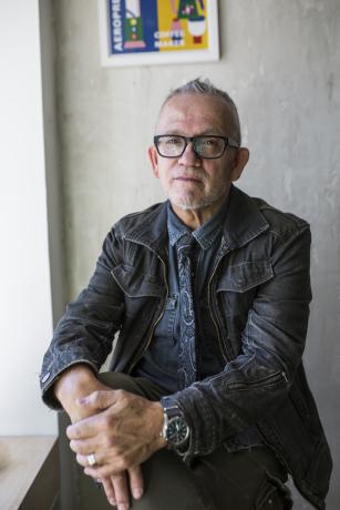 A portrait of an older man with grey hair, glasses, and a black jacket