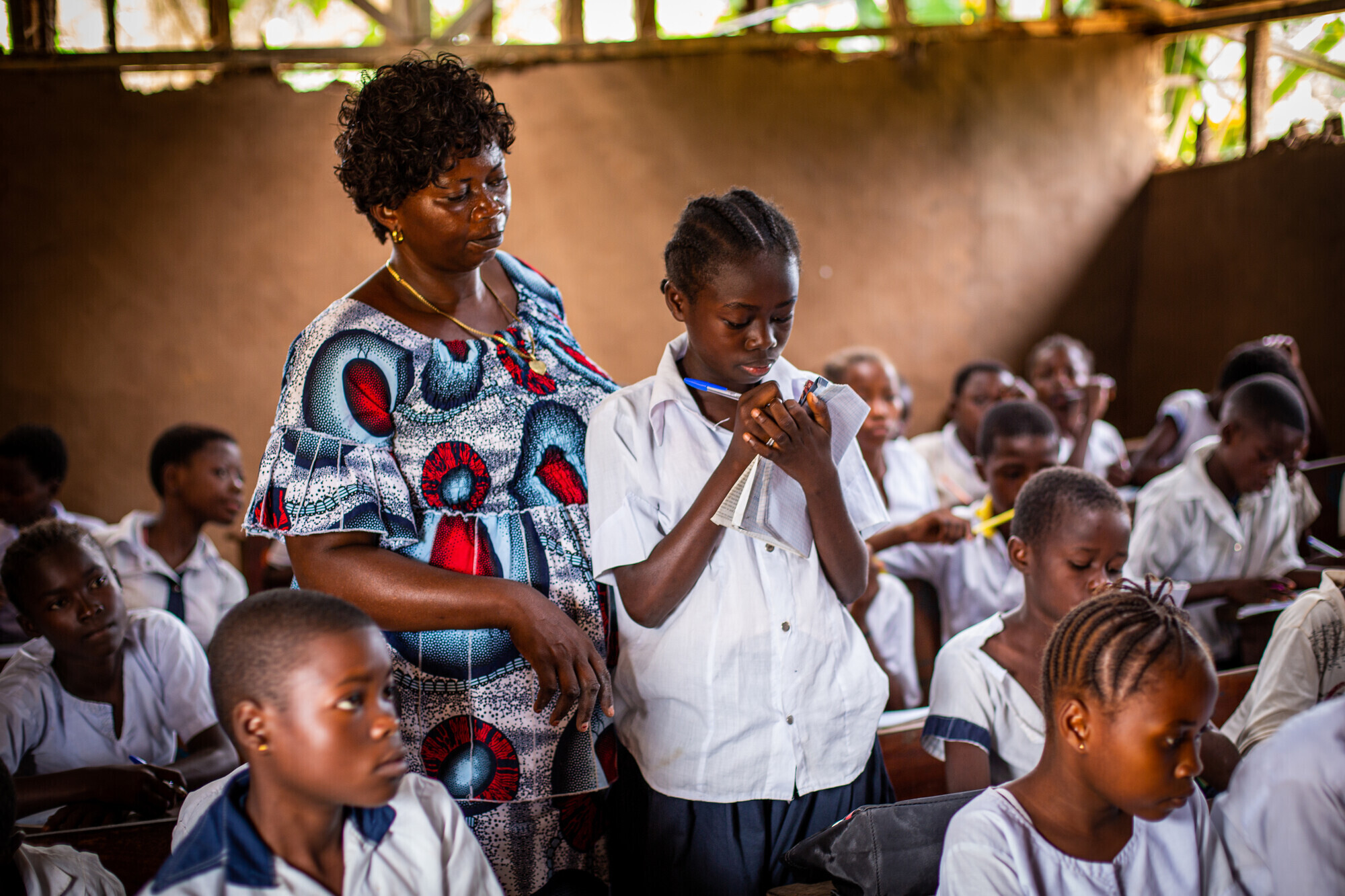 teacher and girl standing among other sixth grade students