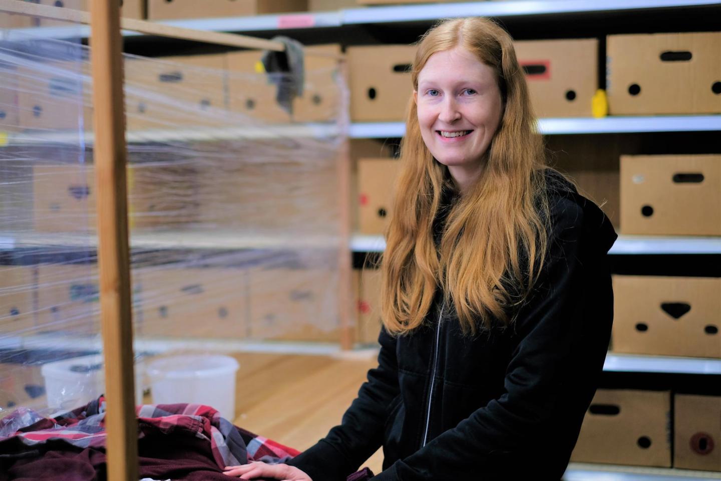 A woman with long red hair works in a thrift shop