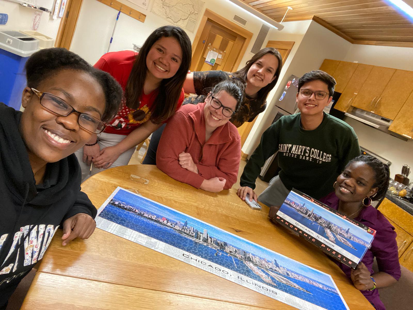 A group of people posing for a photo by a set of puzzle.