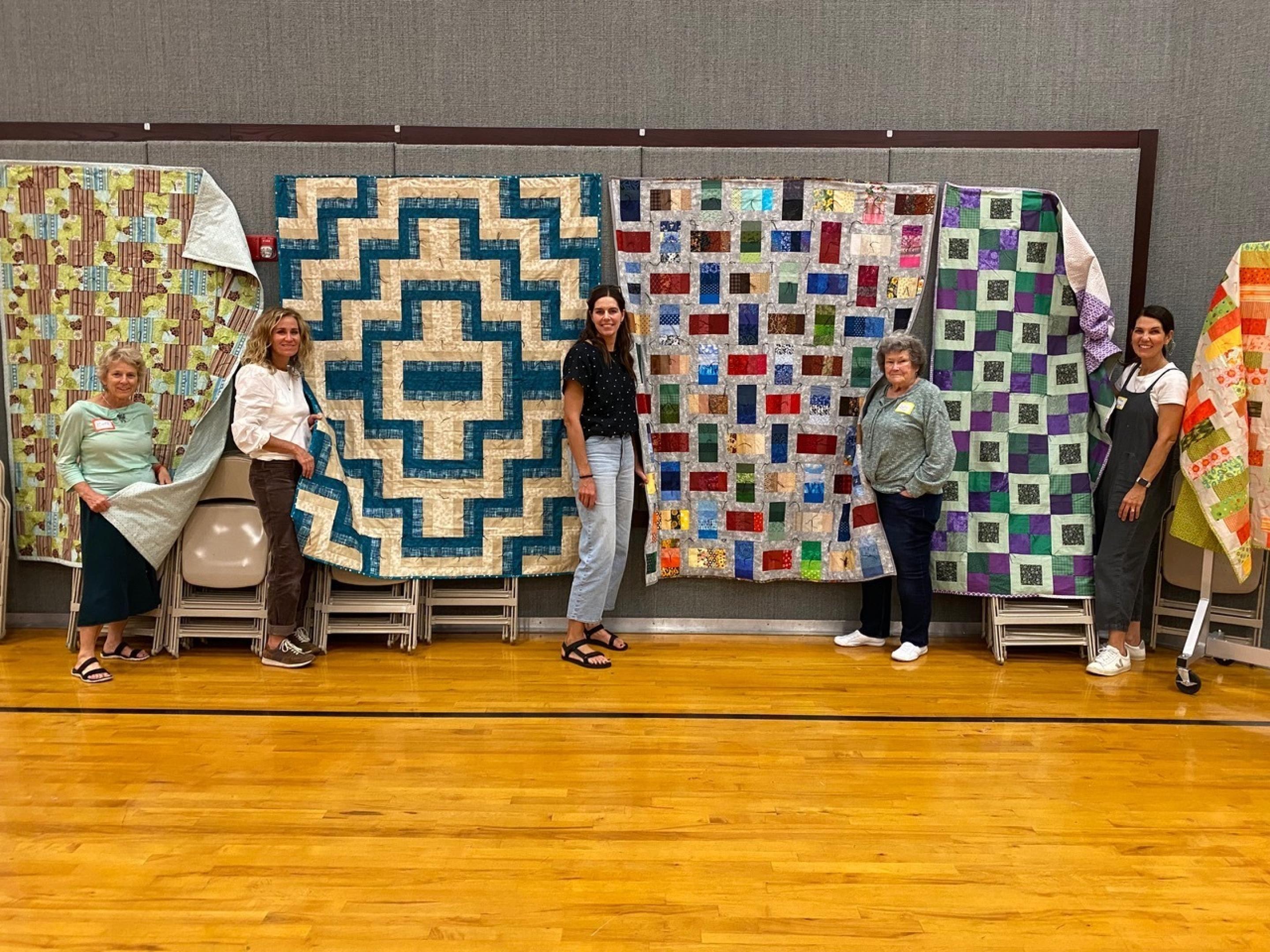 Women displaying quilts