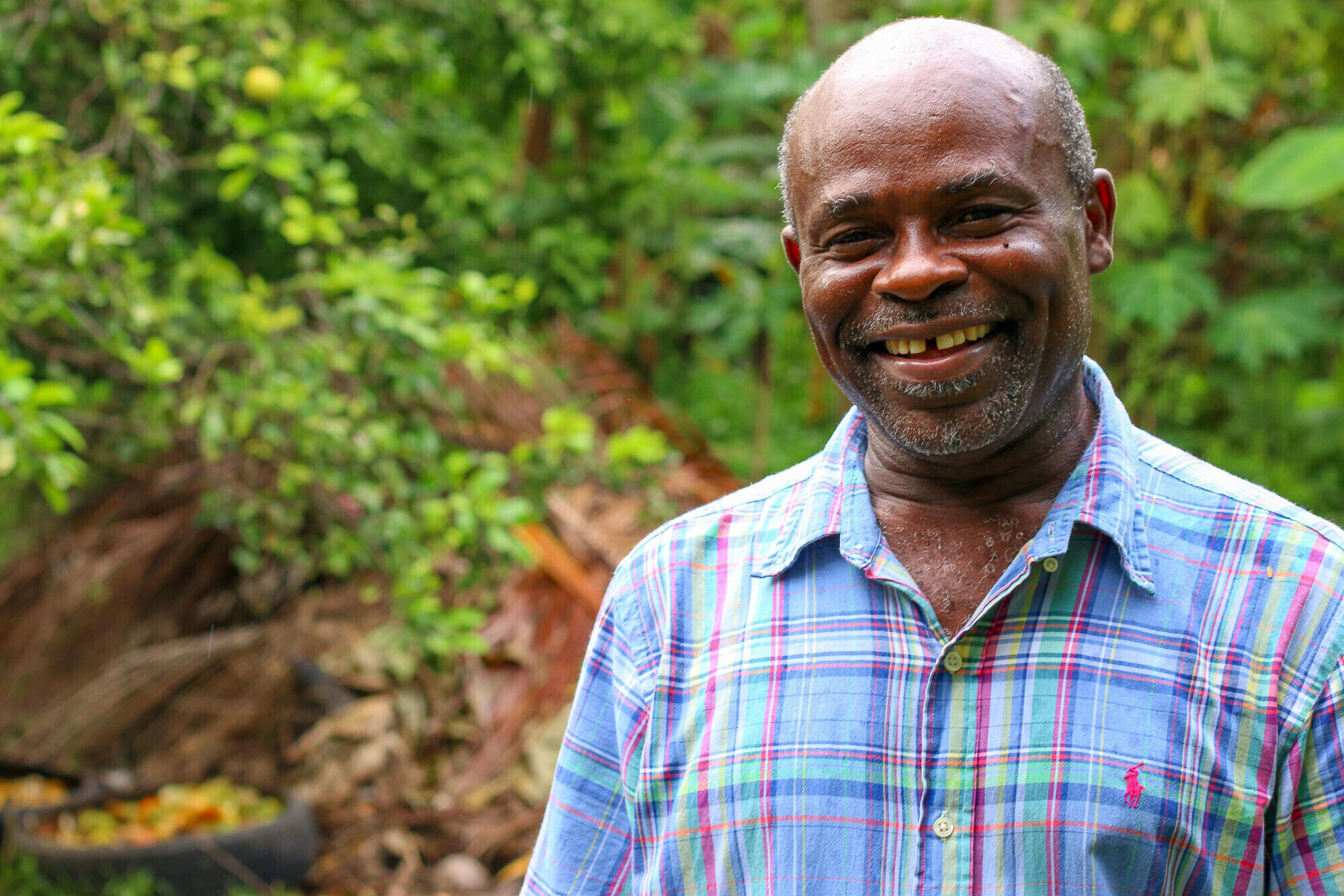 A portrait of a Haitian man in a blue plaid shirt