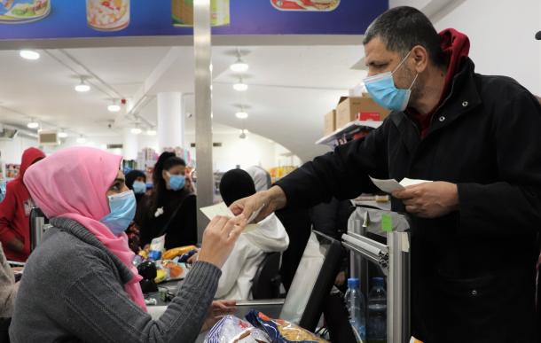 A man pays a woman cashier at a grocery store