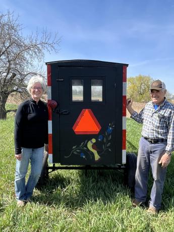 A older man and woman stand behind an Amish buggy