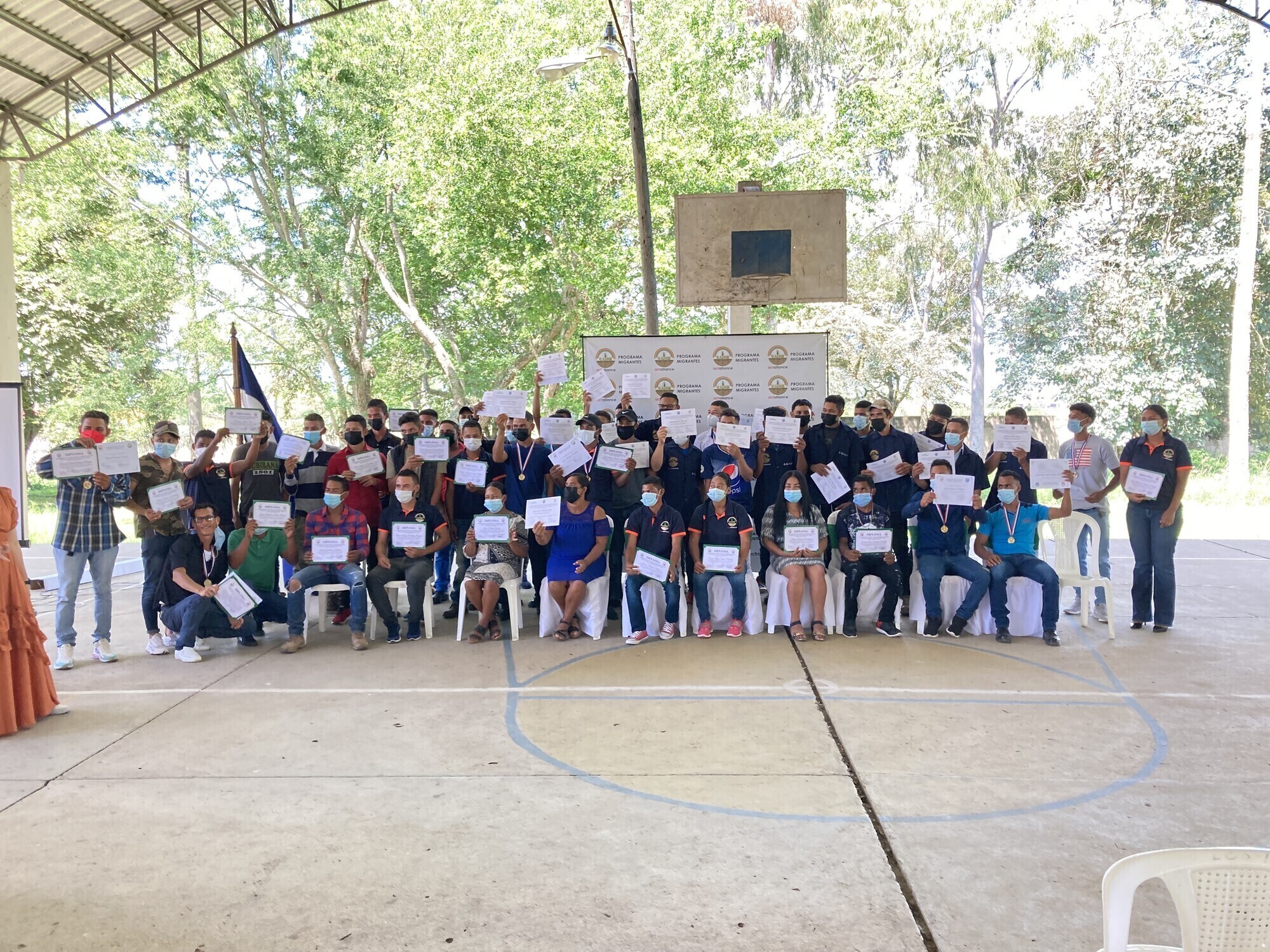 A large group of people at a graduation ceremony. They are all holding their diplomas. 