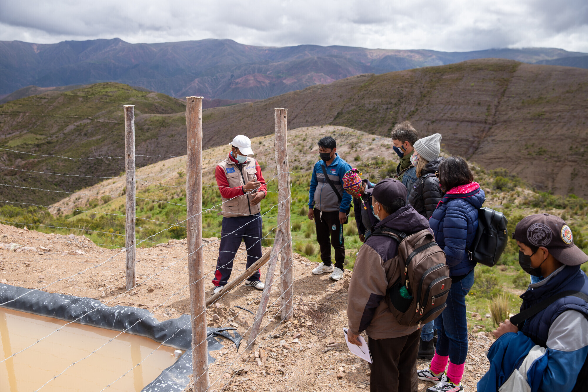 A group of people stand by a fenced off reservoir