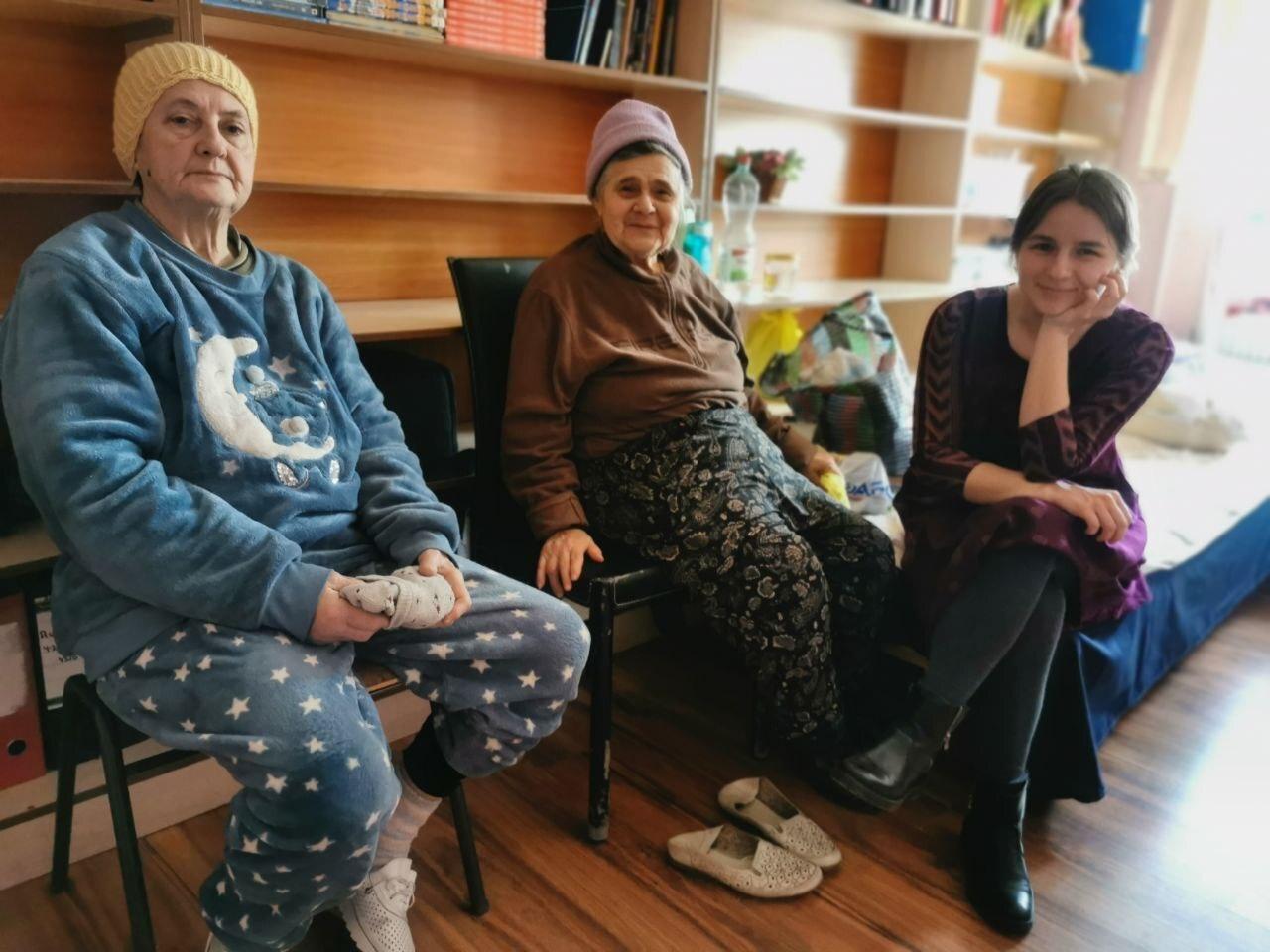 A group of three people sit and look at the camera.