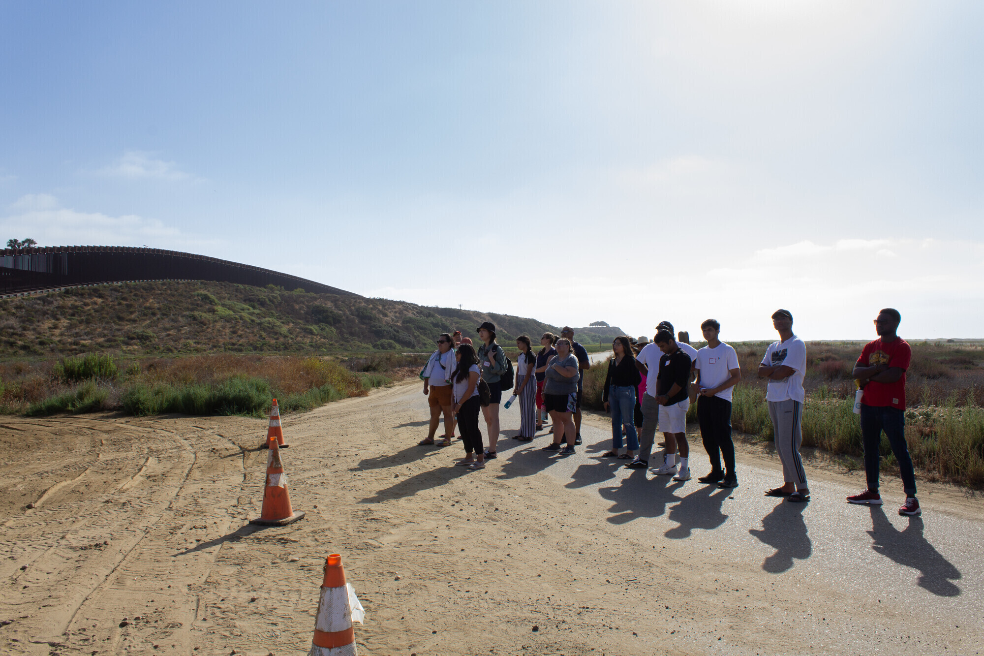 A group of young adults stand in front of orange cones