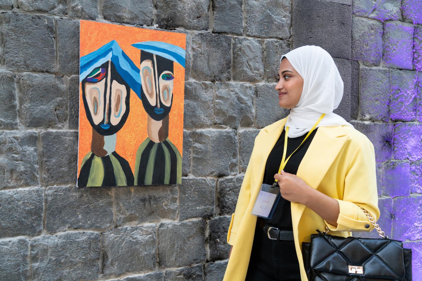 A young woman stands next to a piece of art