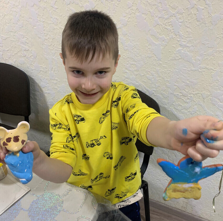 A young boy holding two clay animals