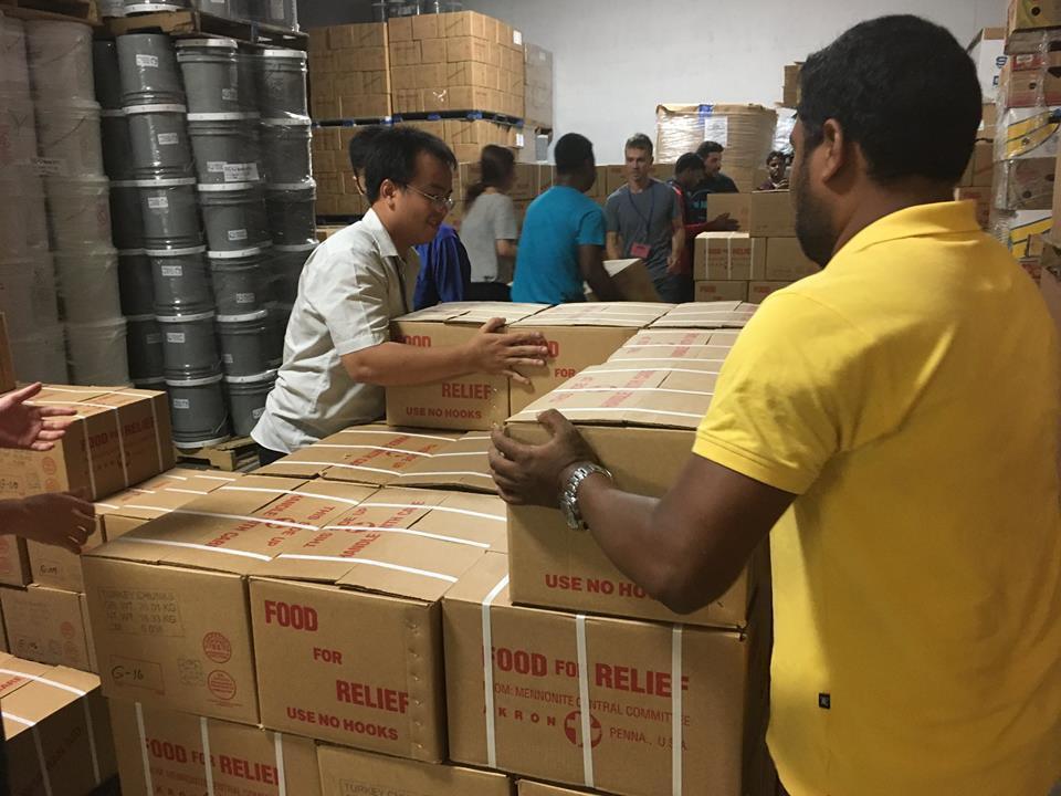 Two young men stack boxes that say "food for relief"