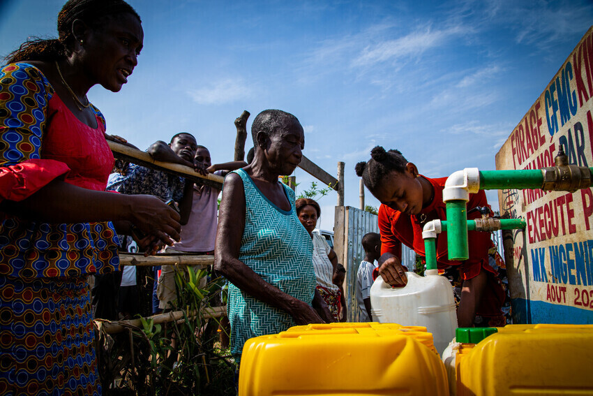 women getting water from a borehole pipe