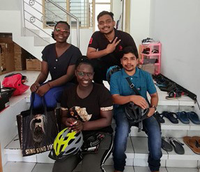 A group of four young adults of different nationalities sit on a set of stairs