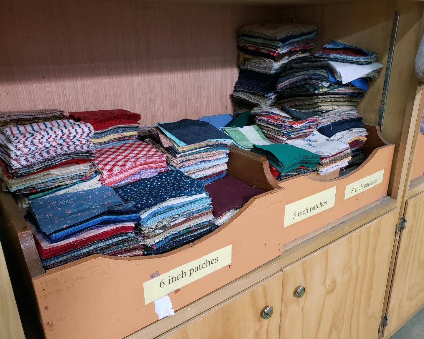 Three piles of cut fabric squares organized by size