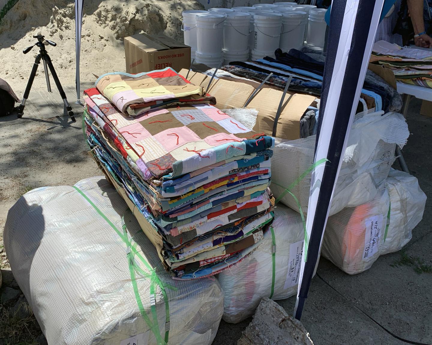 An opened bale of comforters sits on other bales wrapped in white plastic.