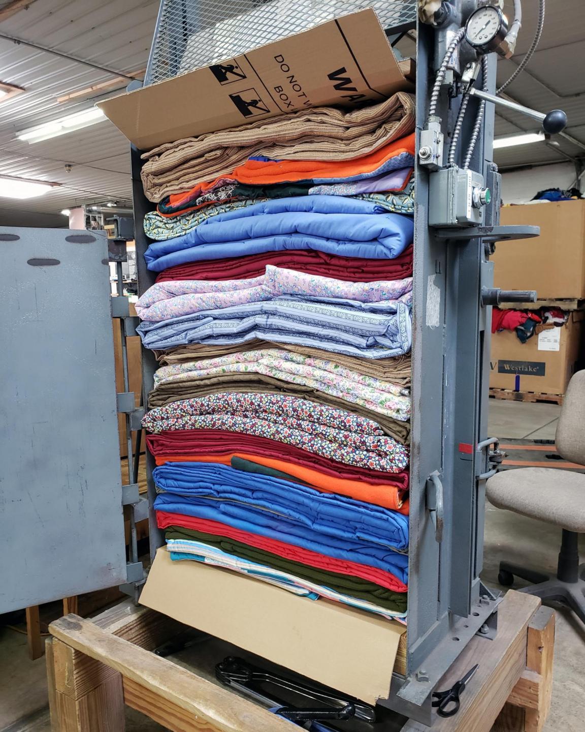 A pile of colorful comforters in a baler