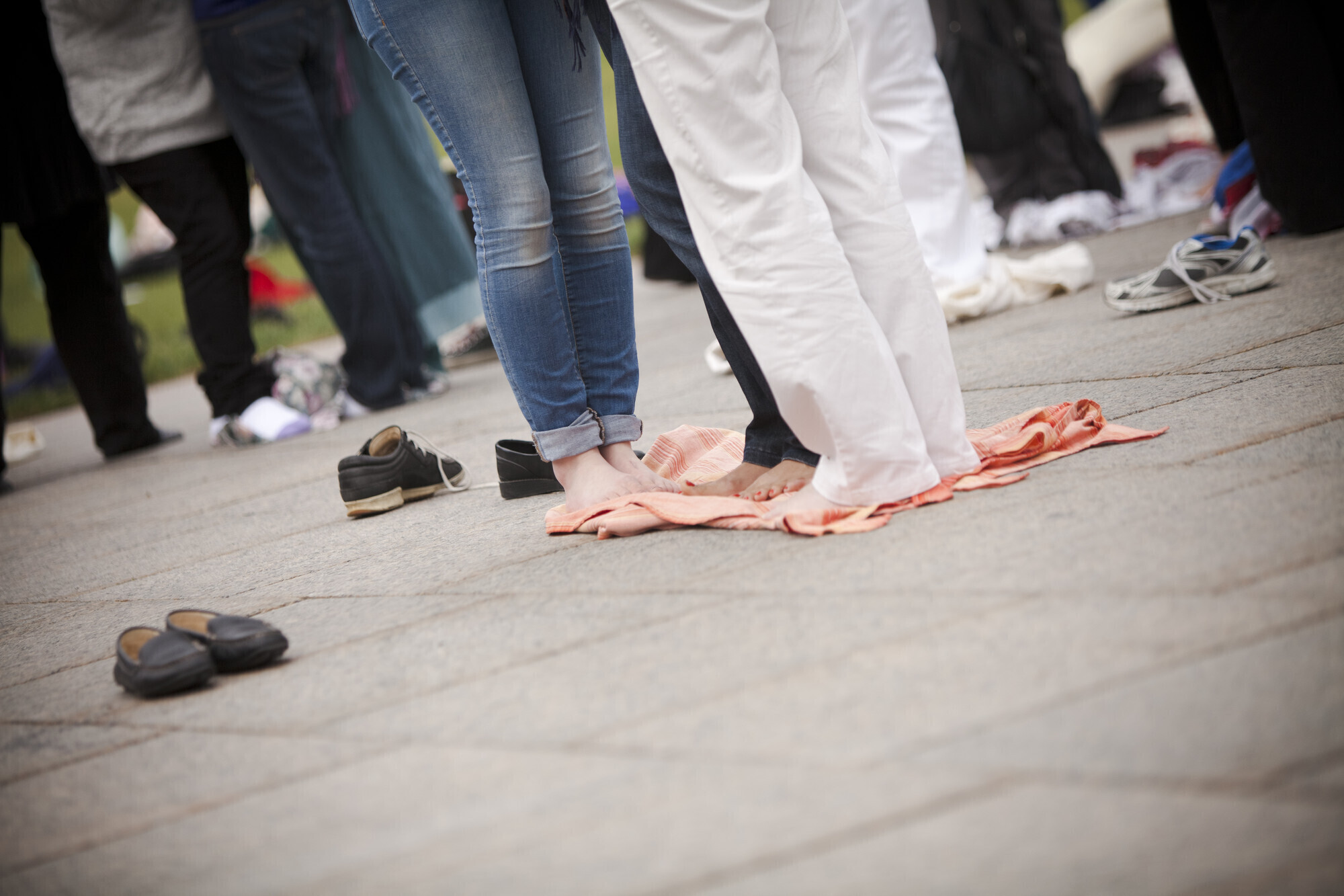 Several people stand close together on a blanket. They aren't wearing shoes.