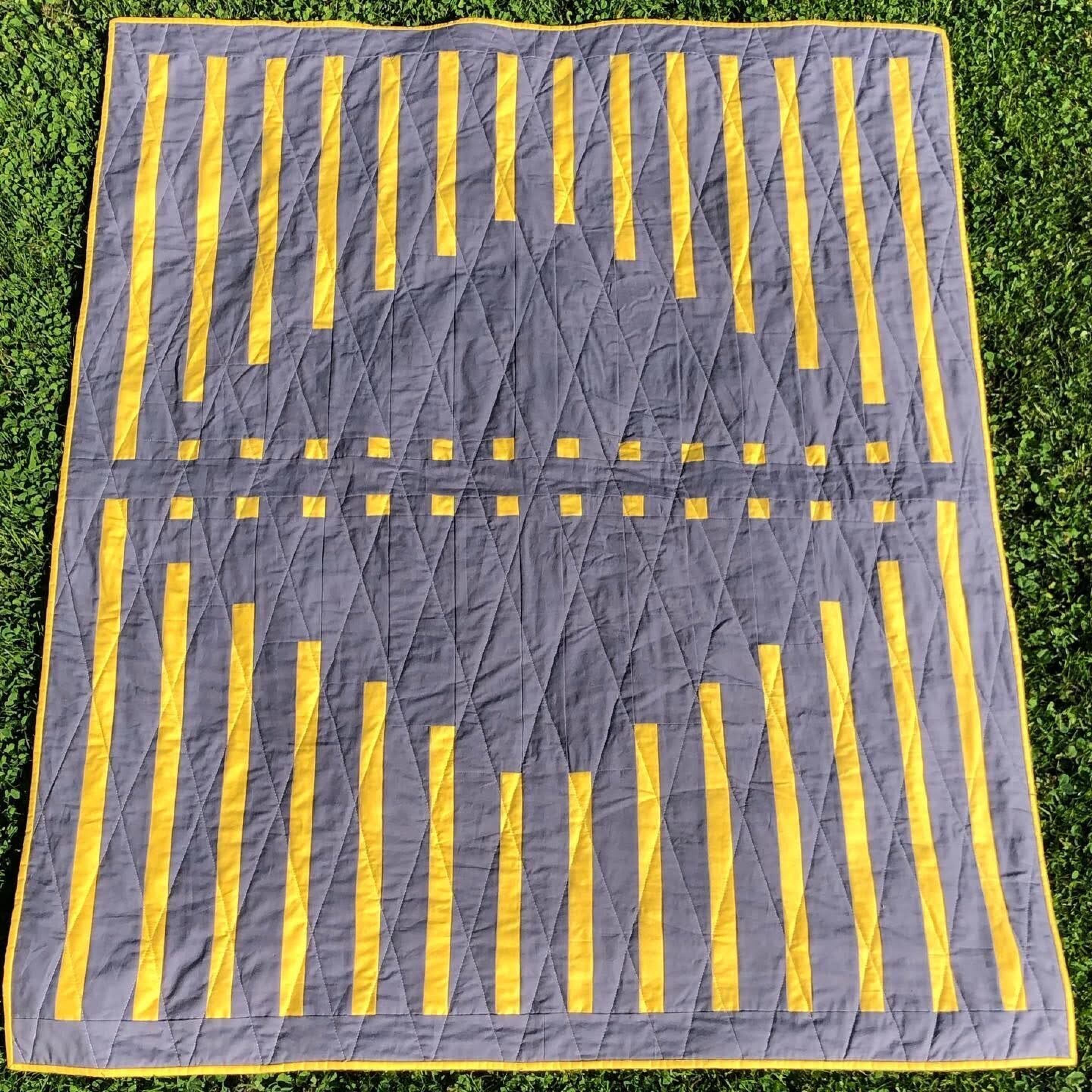 A yellow and grey quilt laid out on the ground