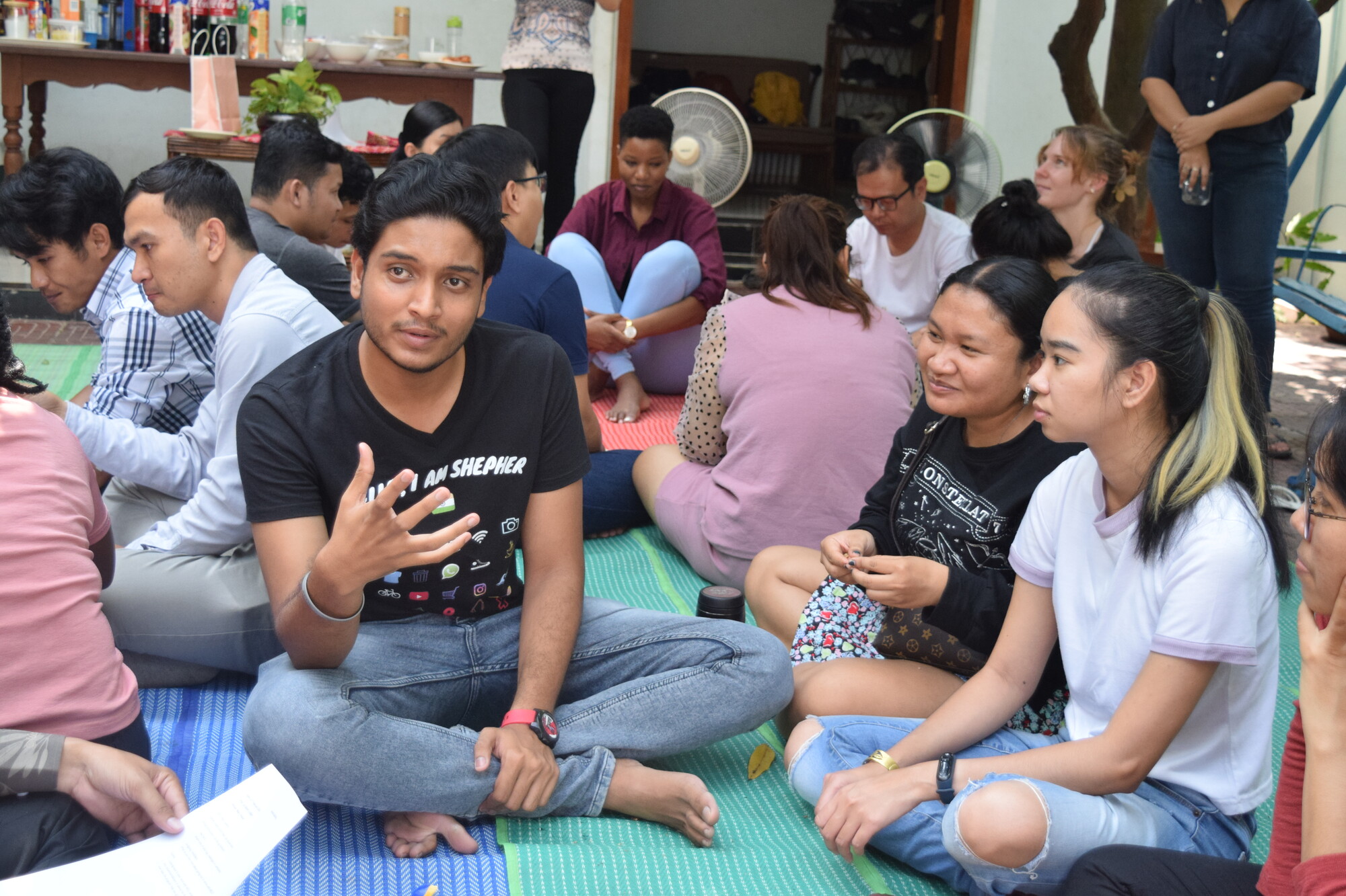 A group of people sitting on a blanket in conversation