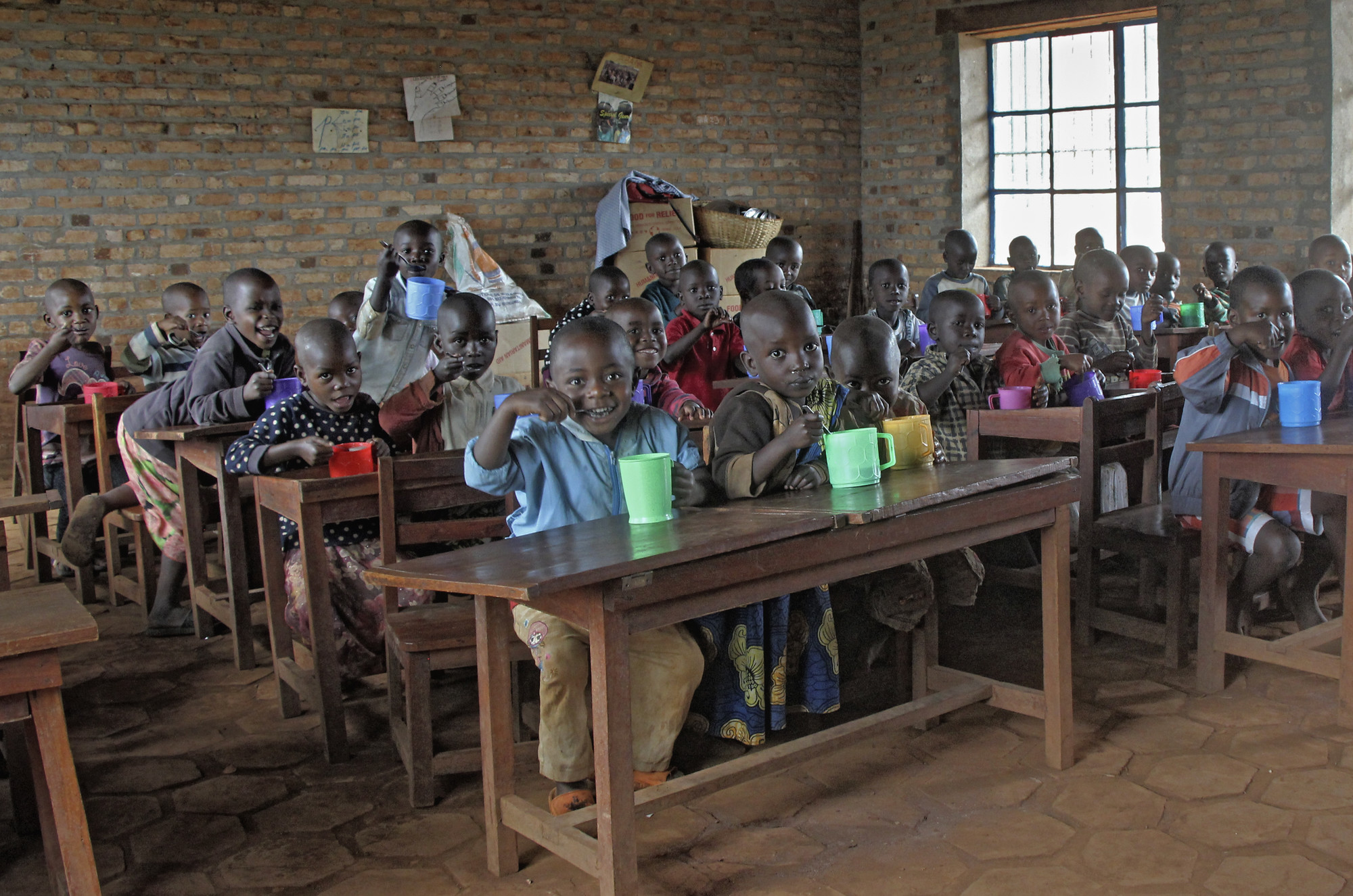 School children in Burundi eat out of plastic mugs in their classroom