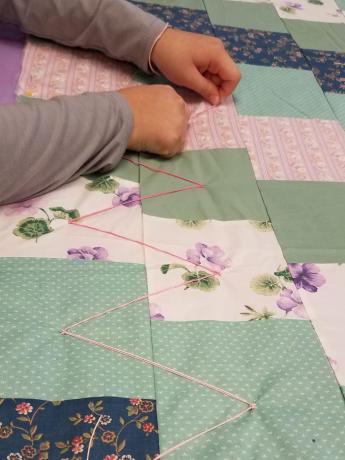 A close up of hands tying a comforter top