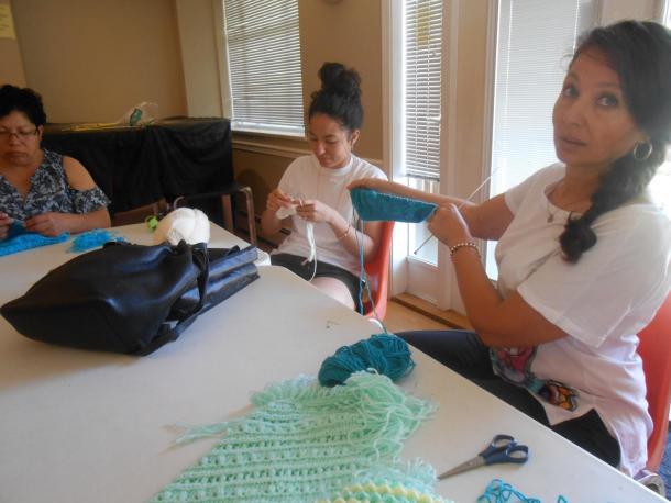 Three women sit at a table and crotch/knit