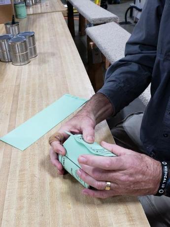 Close up of hands putting a label on a can