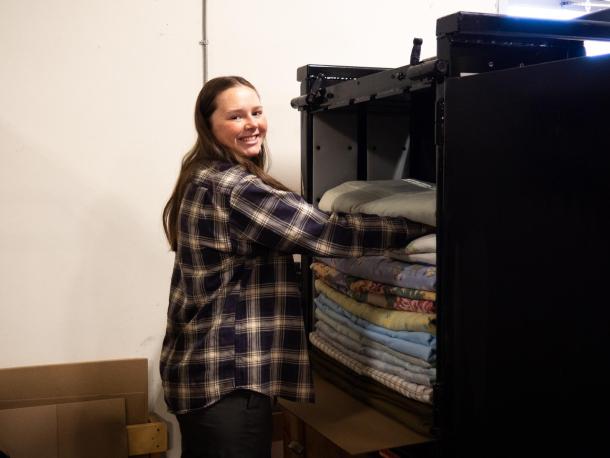 A young woman stacks comforters into a bailer