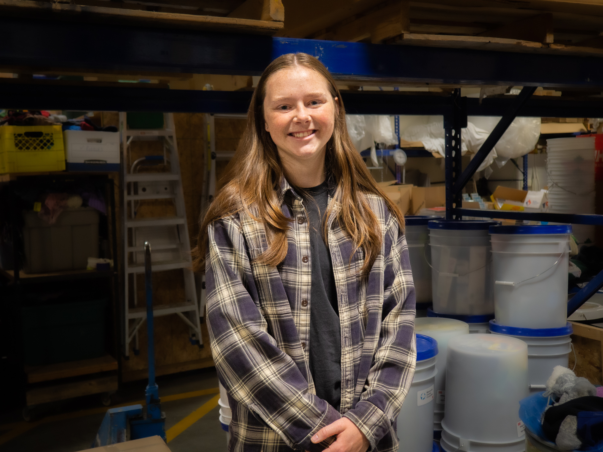 A smiling young woman in front of relief buckets.