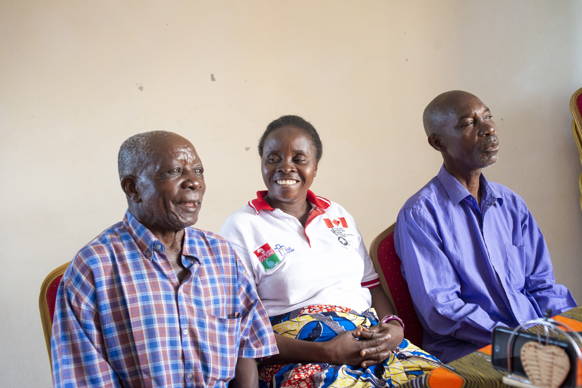 Woman and two men sit together, smiling. 