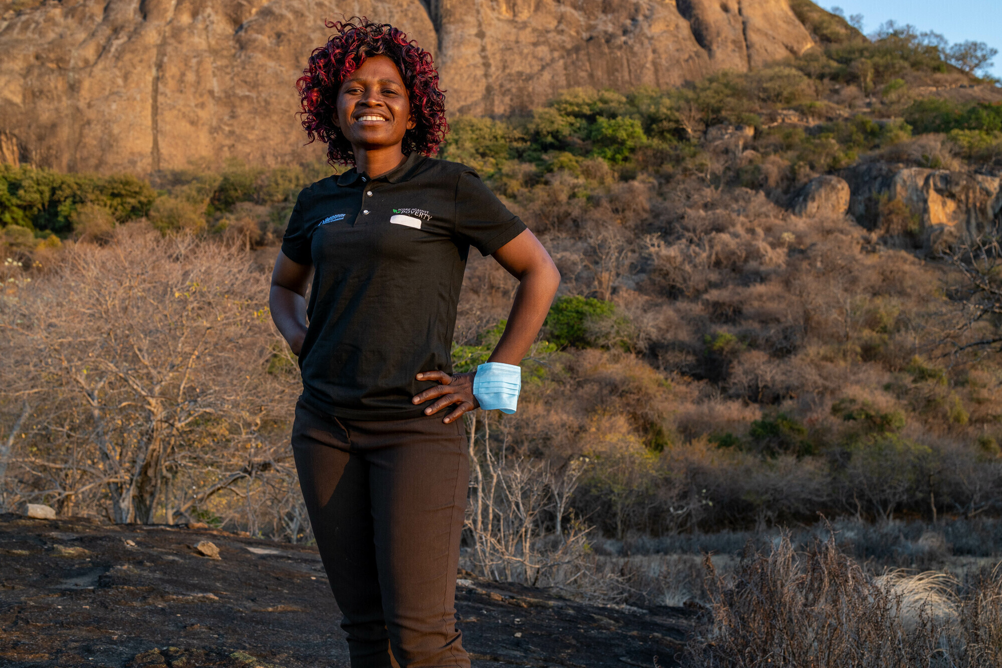 A woman standing in front of a rocky hill