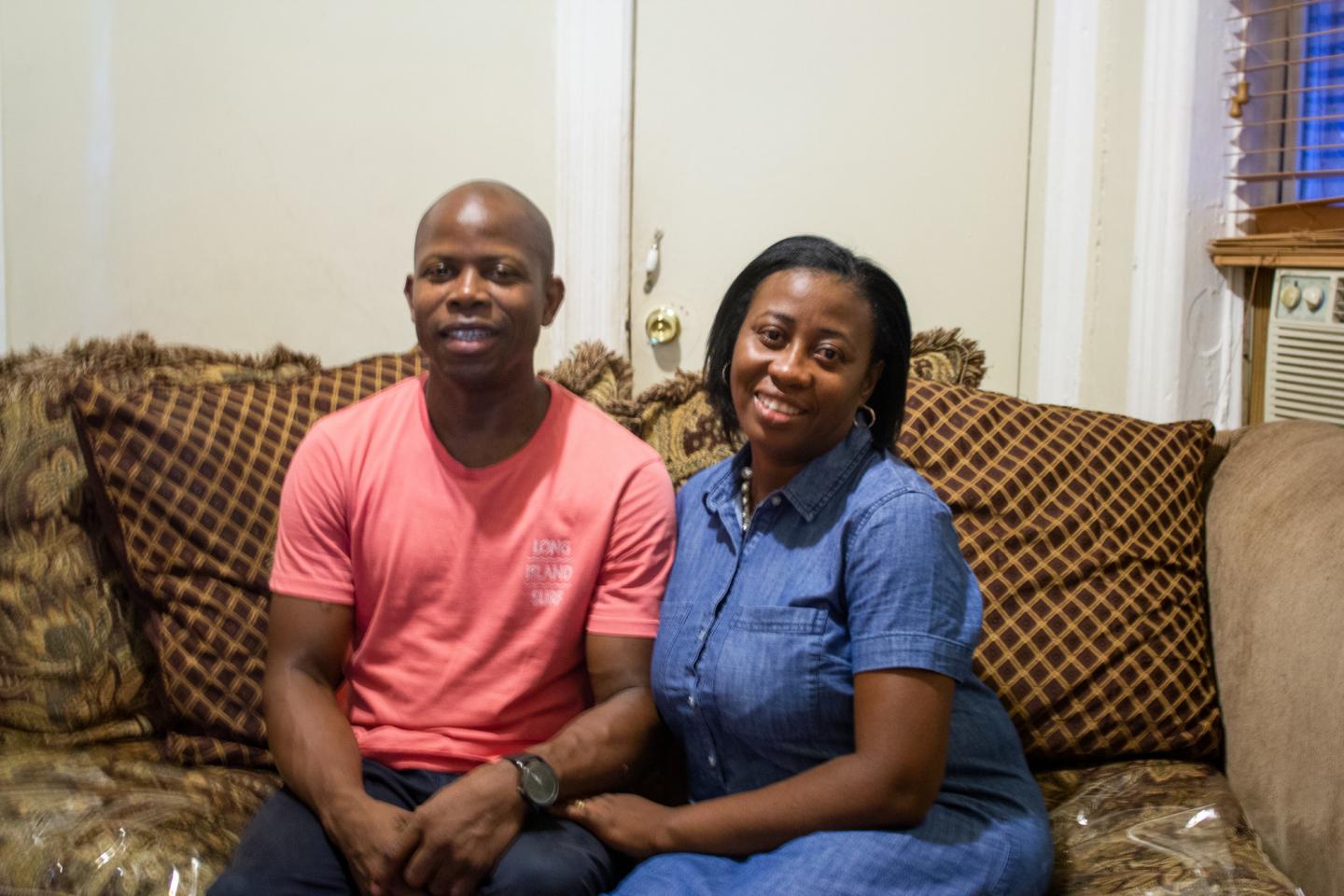 A man and woman sit together on a brown couch