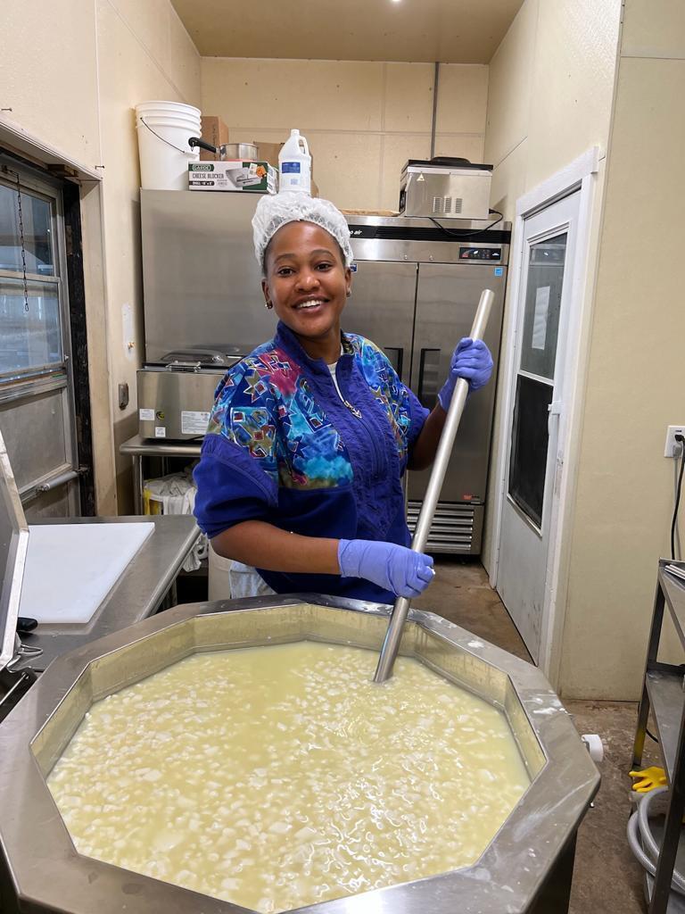 A woman stirring a large vat of dairy