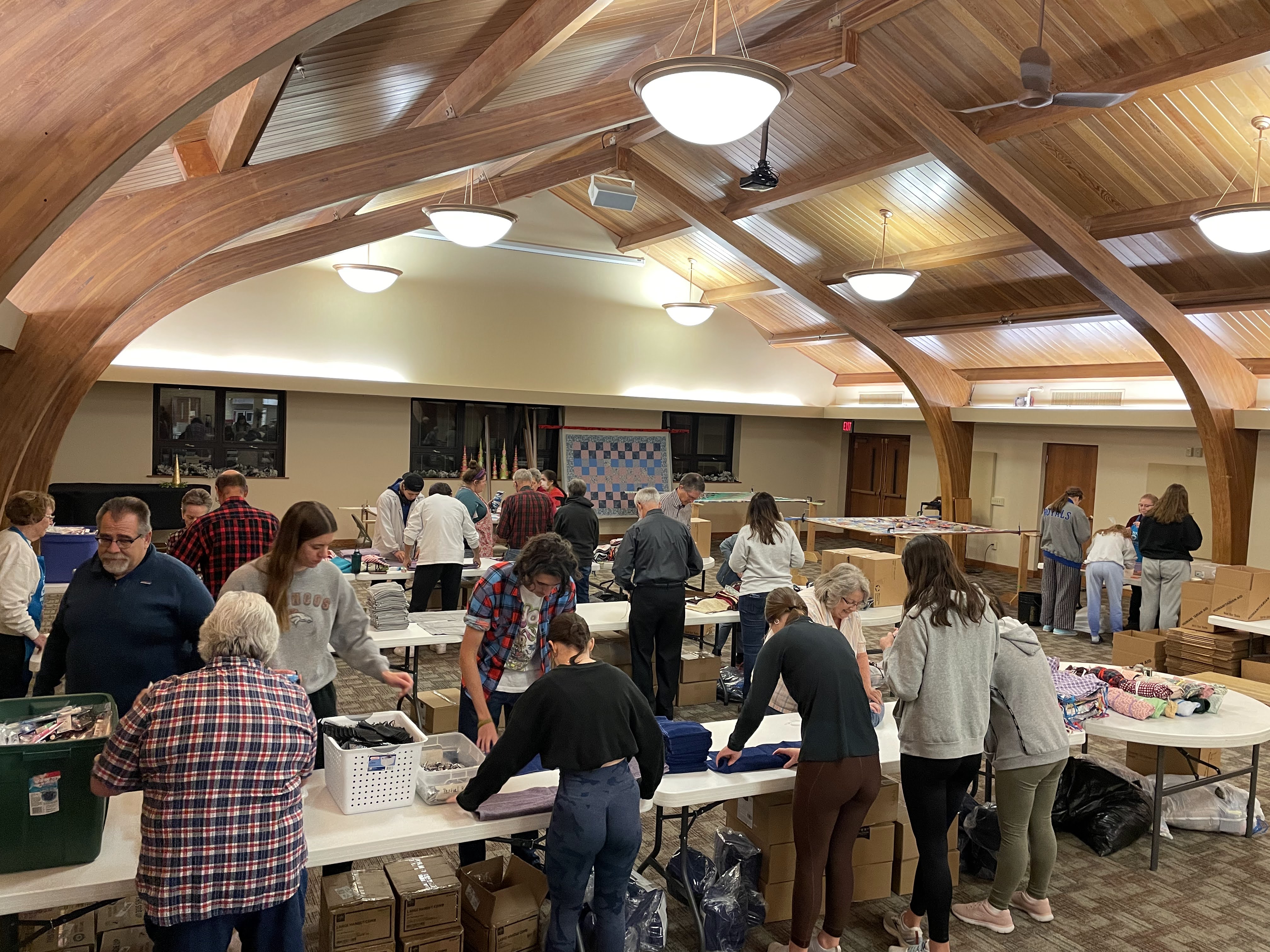  A group of volunteers assemble hygiene kits in large room.