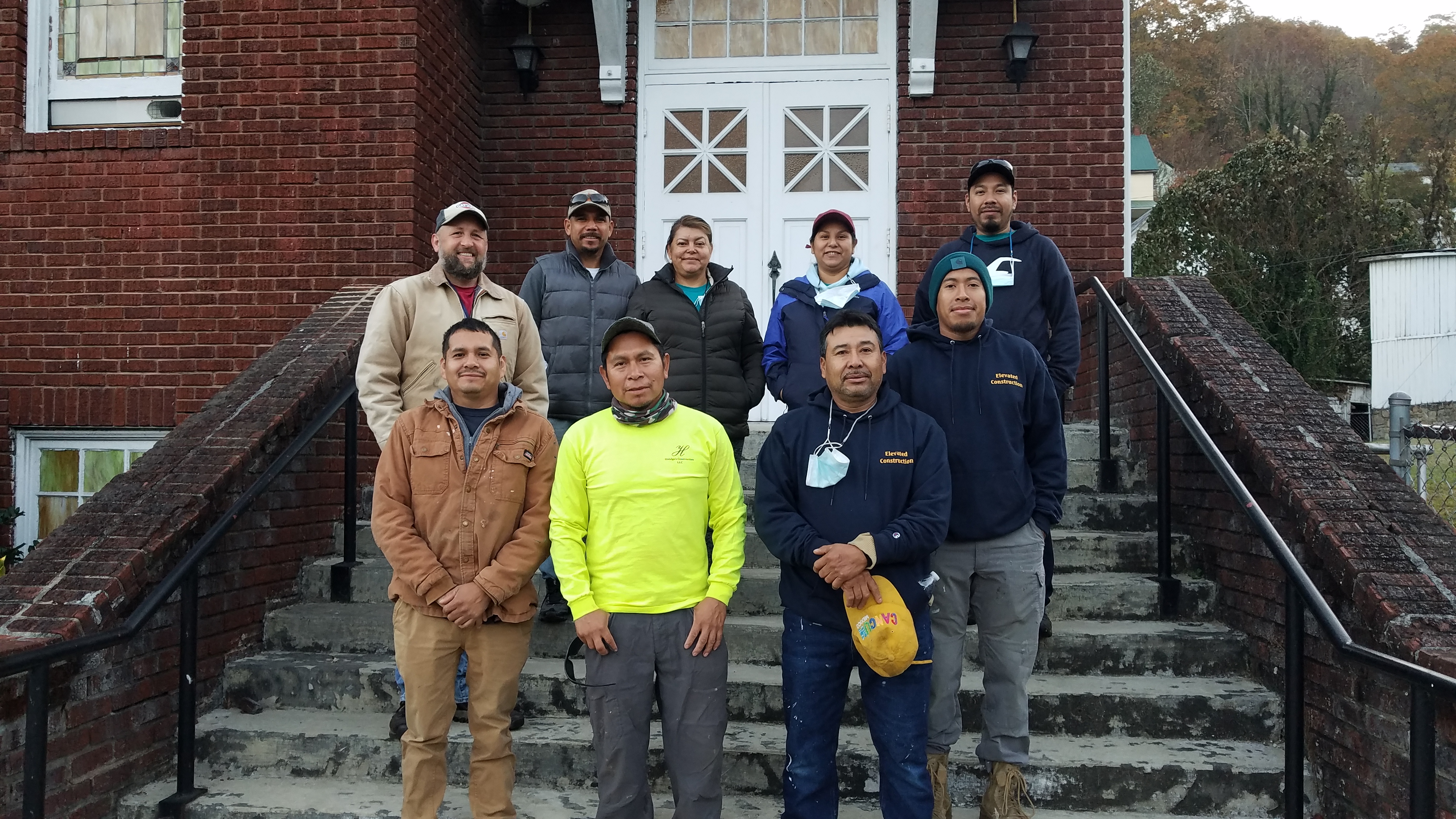 group of people stand on steps in front of a building and smile at camera