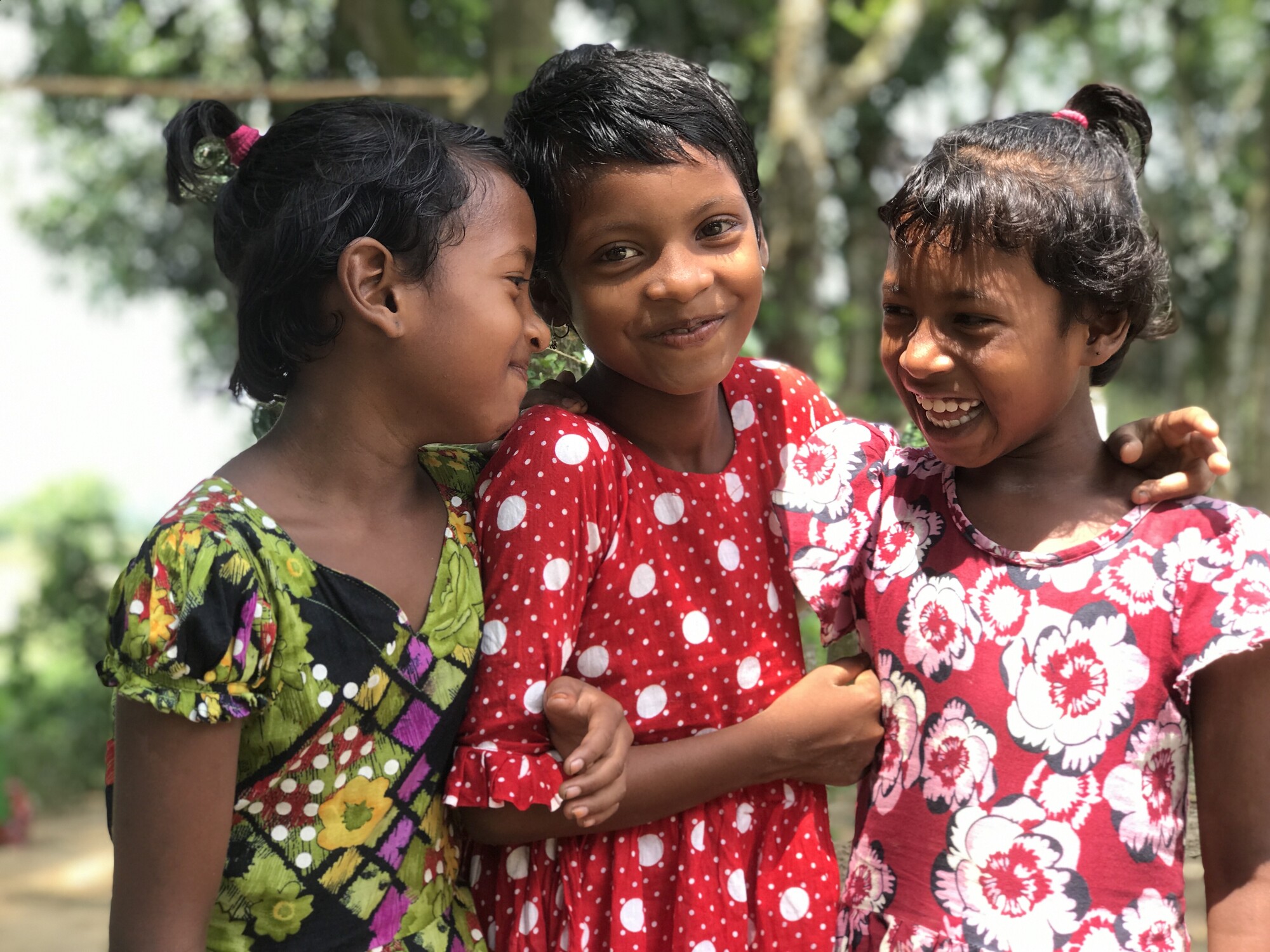 Three young girls smiling and hugging