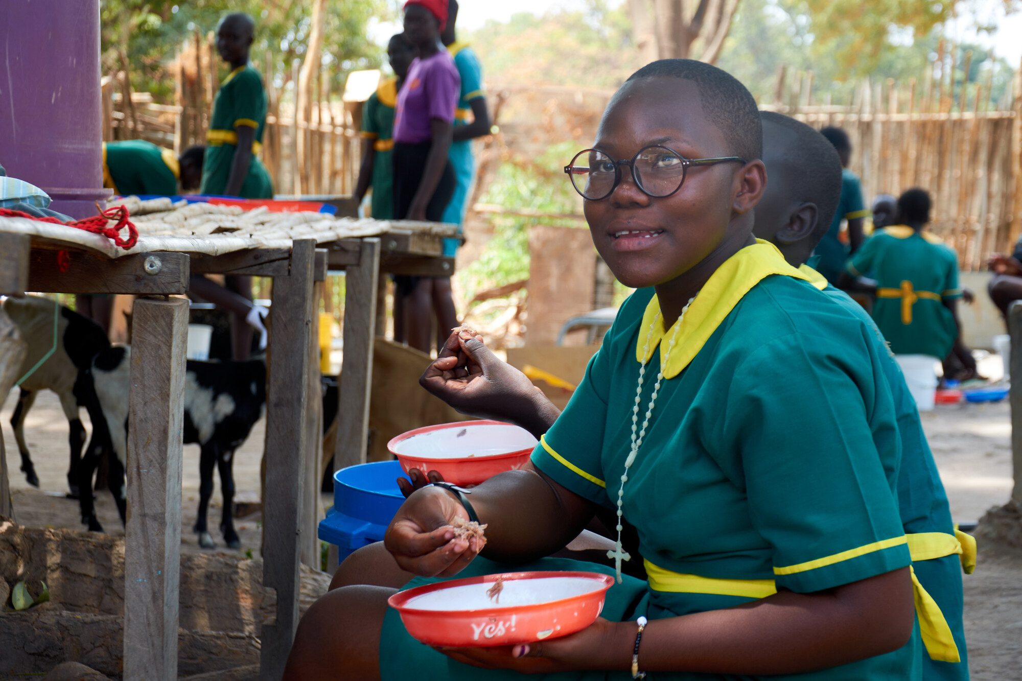 A young girl eats food from a shallow bowl