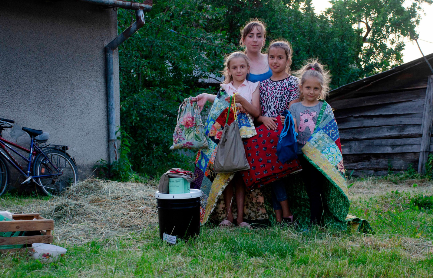 A woman and three children holding comforters