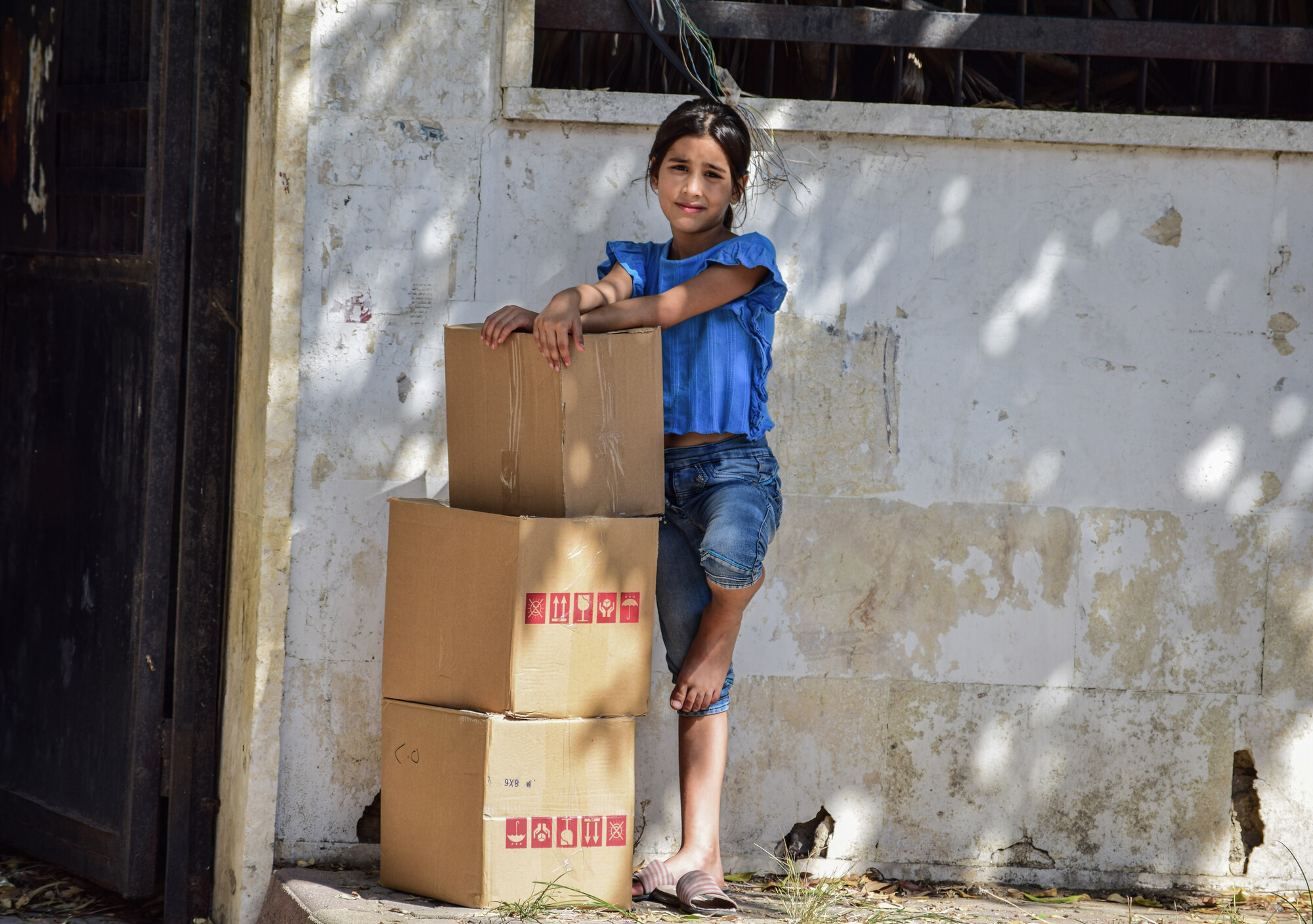 A young girl standing with three boxes of relief supplies