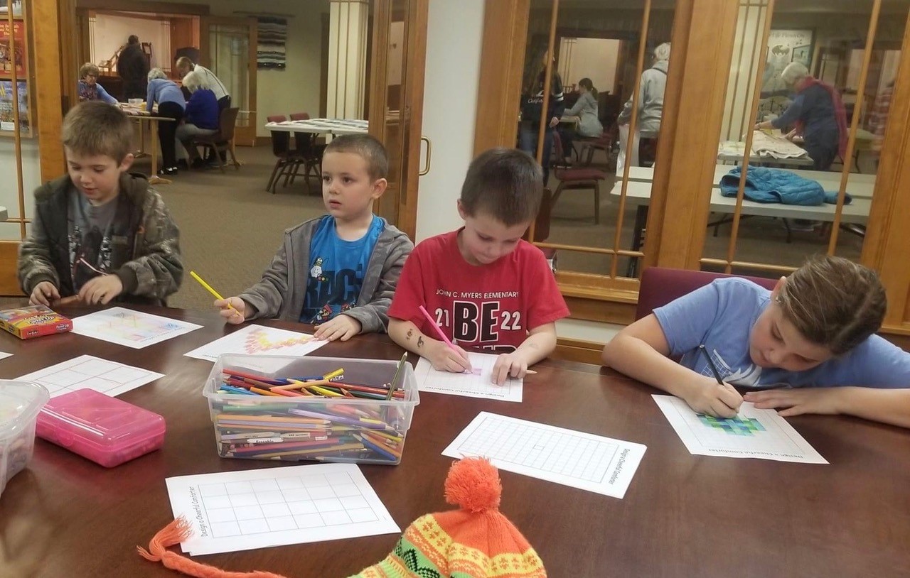 Children coloring in comforter design grids. 