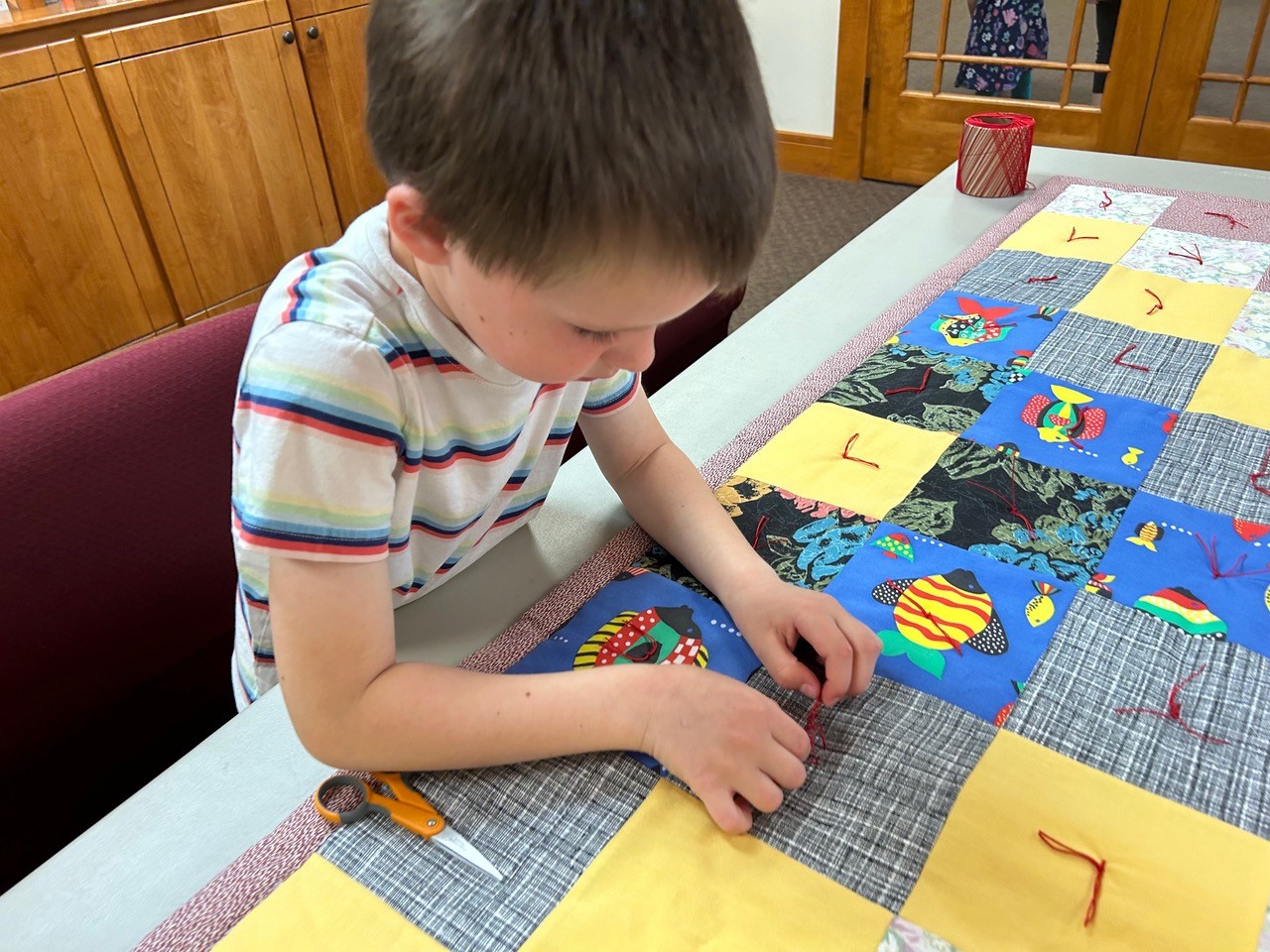 Isaac knots the comforter he designed. 