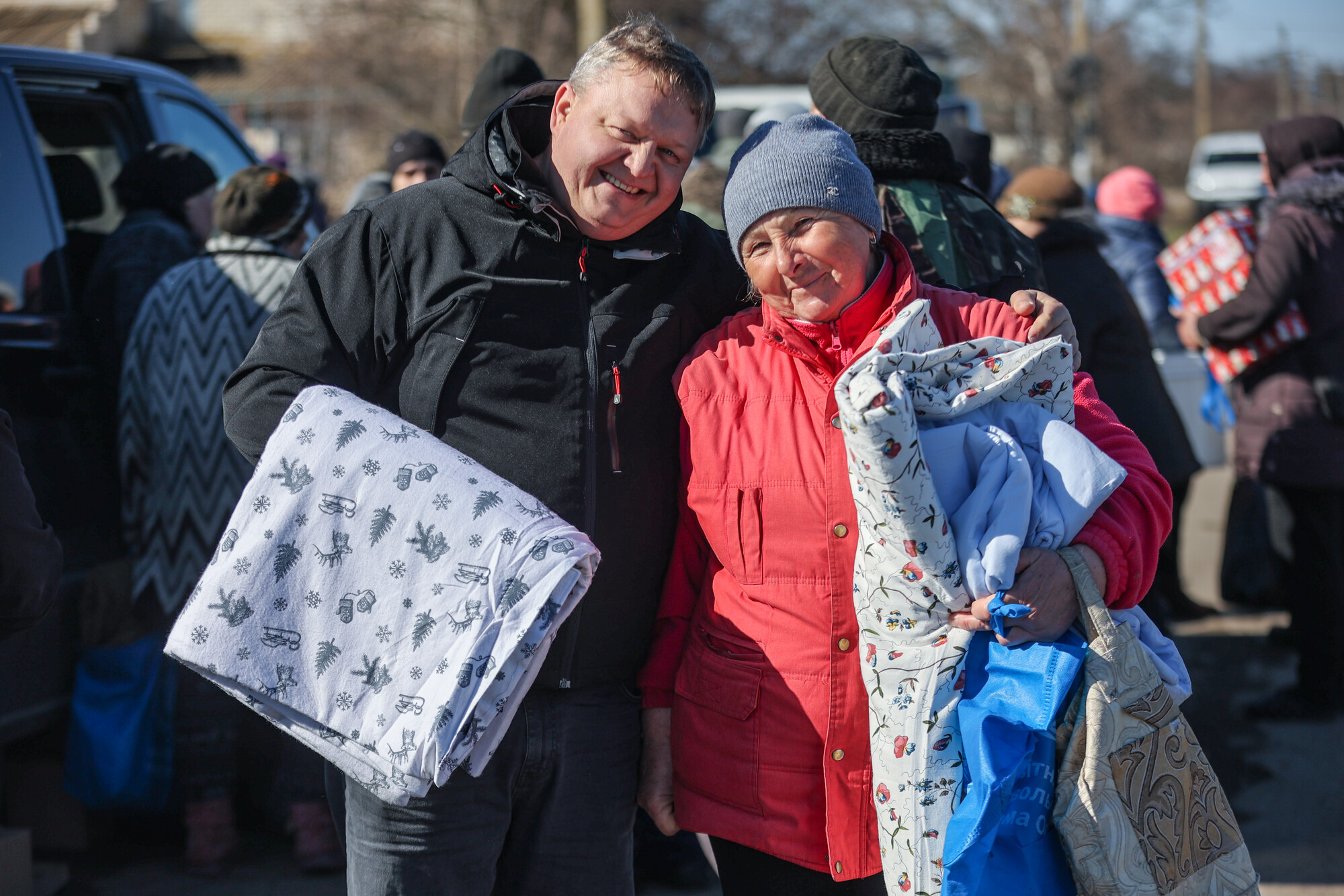 A man and woman smiling holding comforters