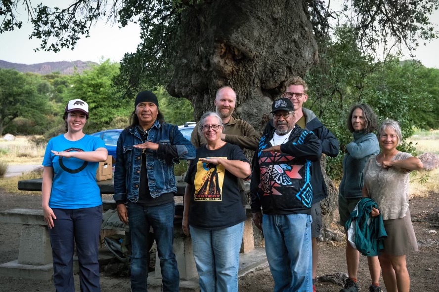 A group of people holding out their right arms in a straight 'level' fashion