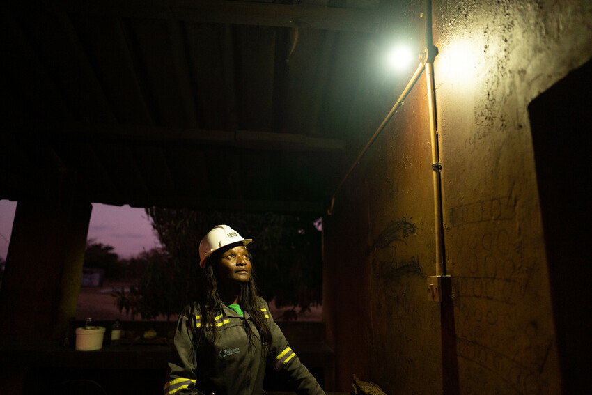 A woman looking at a lightbulb outside in the evening