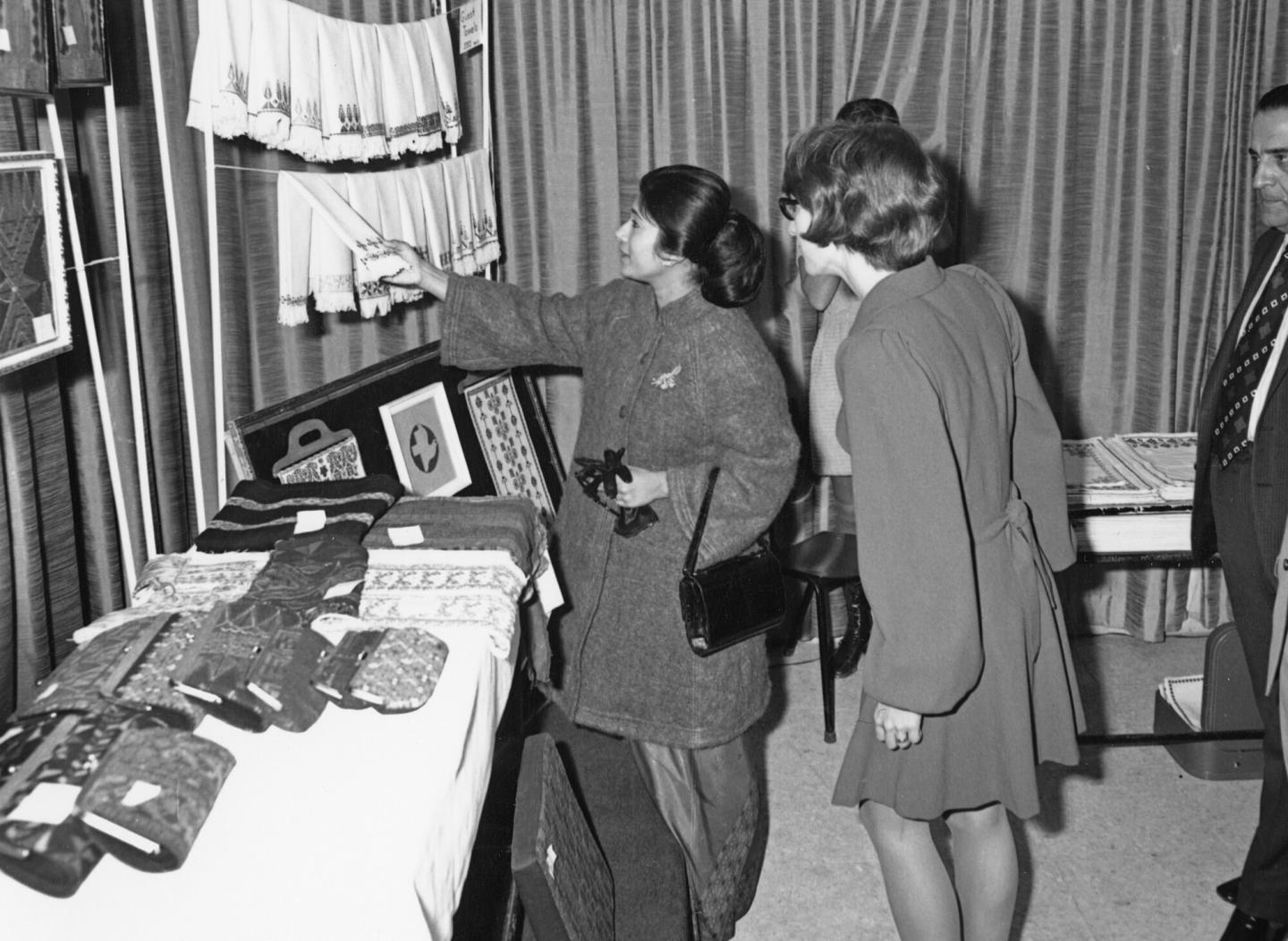 A black and white photo of two women examining sewn items