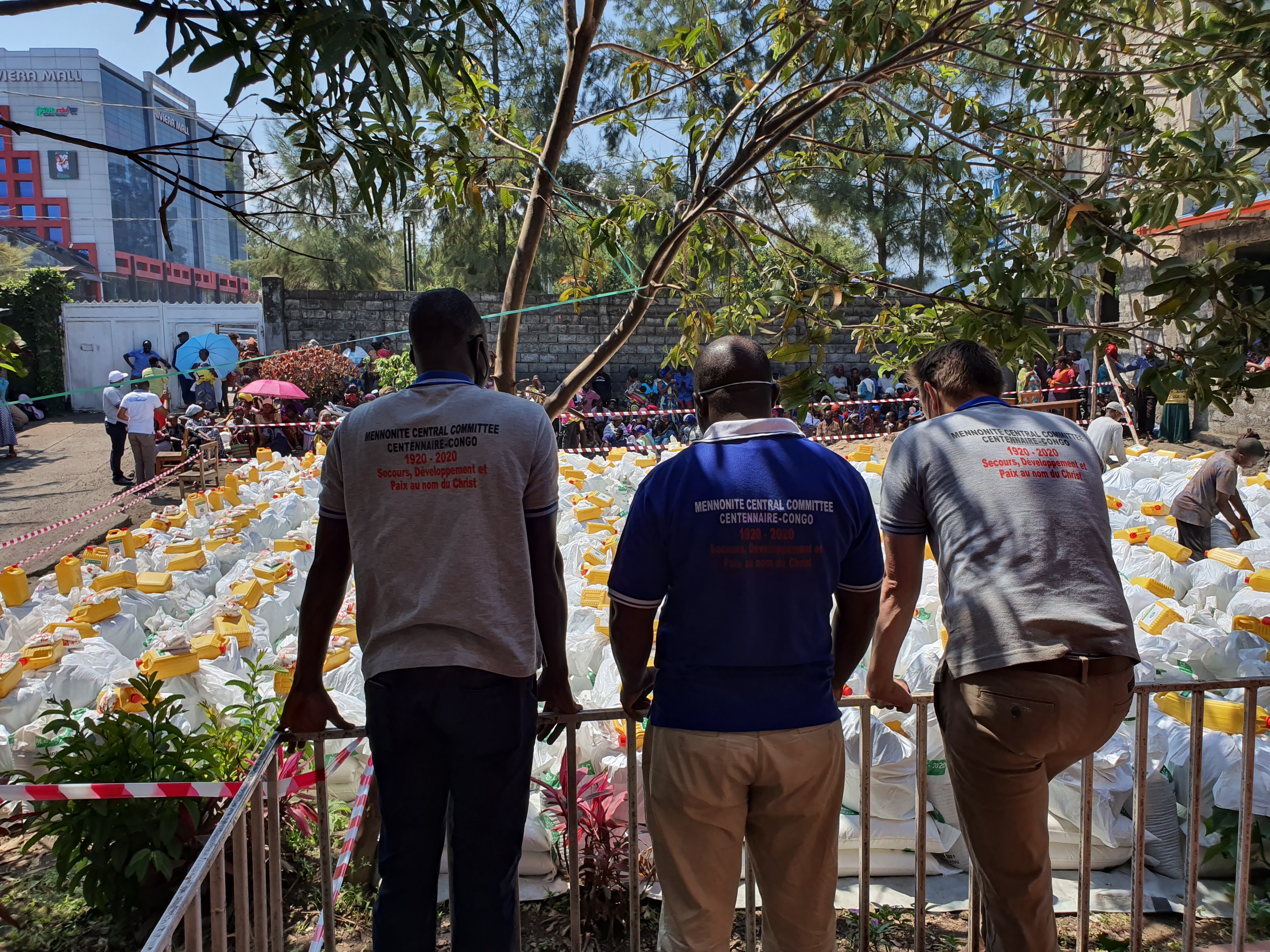 Three people stand with their backs to the camera facing a collection of emergency relief items.