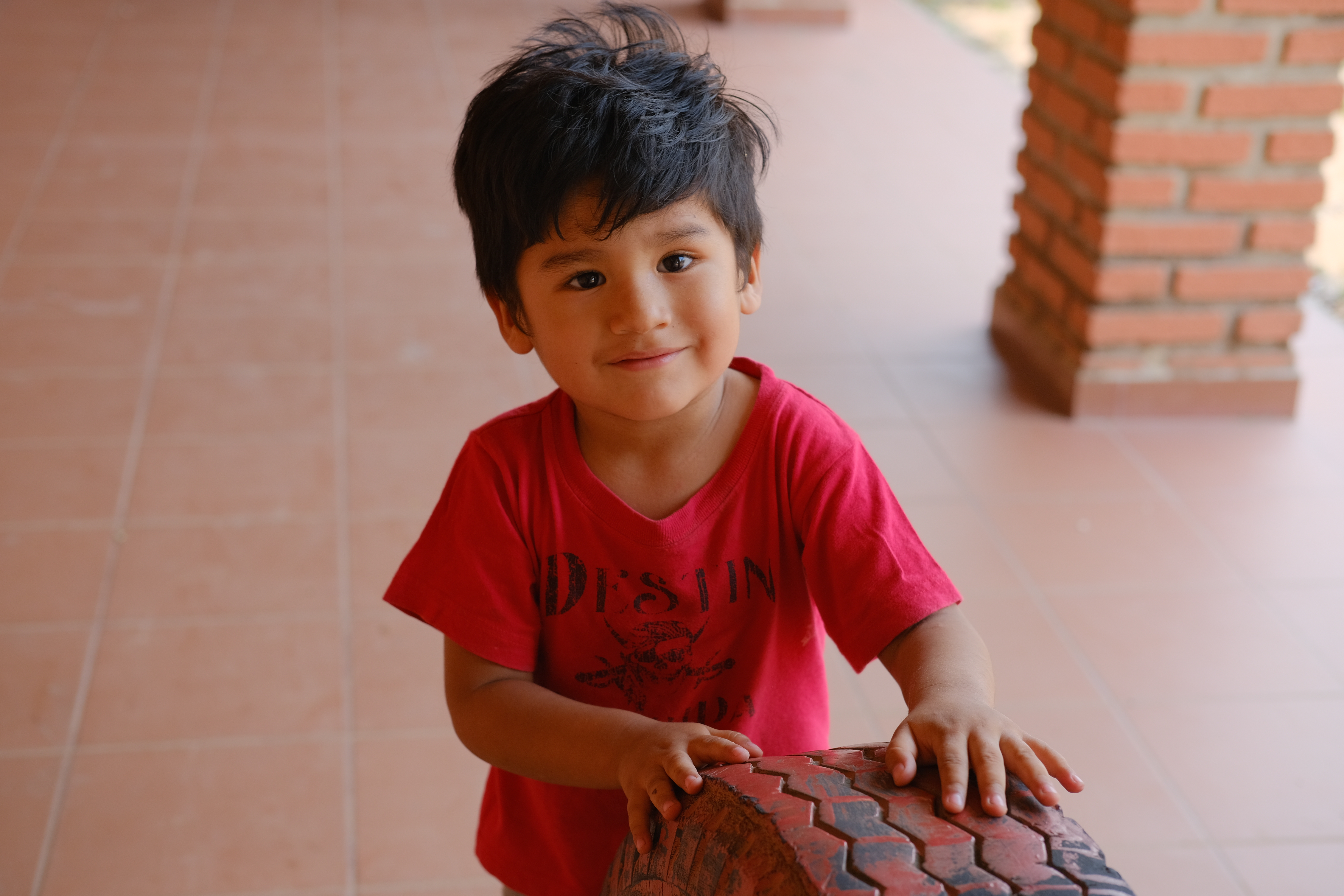 A portrait of two-year-old Basthian Raul Alborta Rodriguez makes a game of rolling a tire at Samuelito Daycare in Santa Cruz, Bolivia